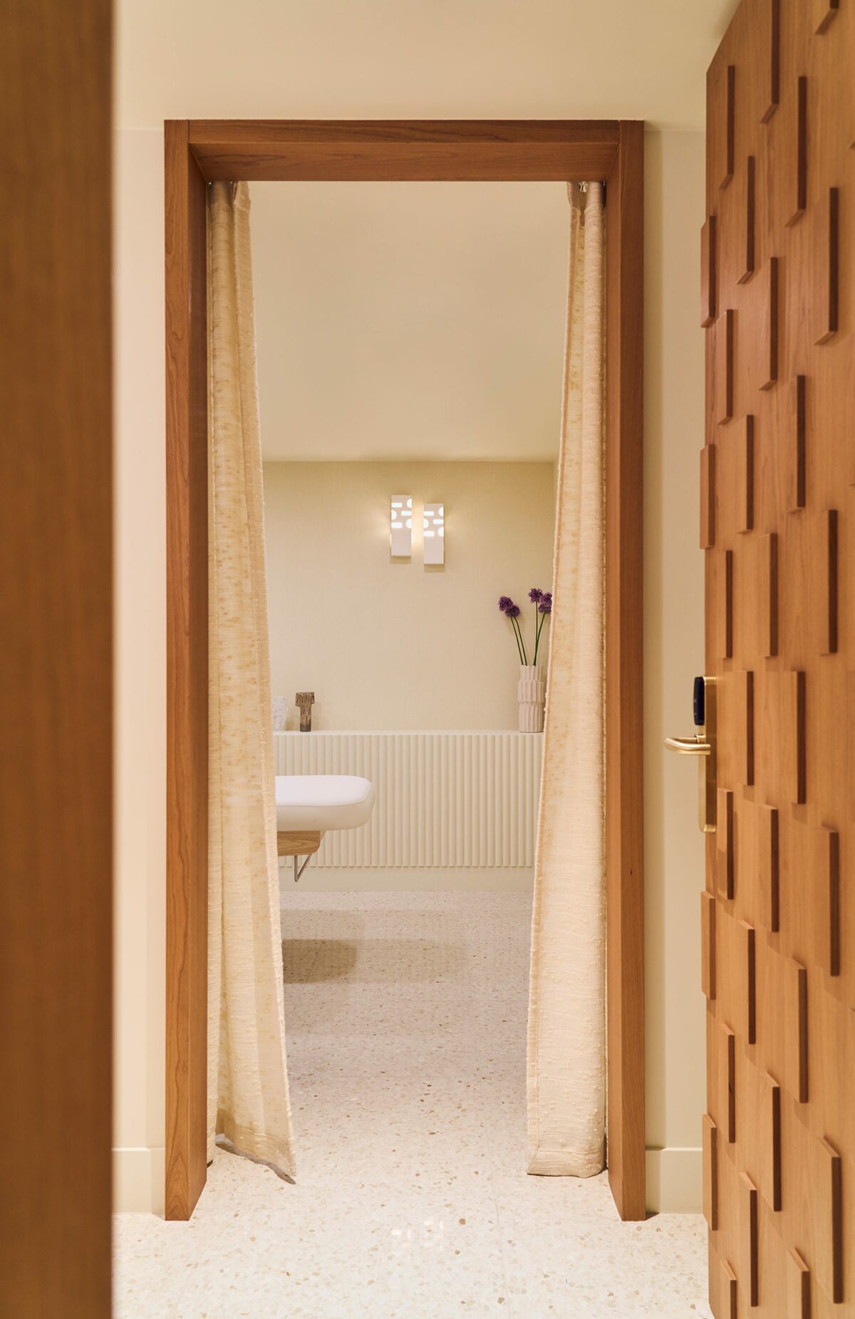 Salle de massage avec rideau en textile en relief et porte en bois sculptée - Projet Montalembert réalisé par Batiik Studio