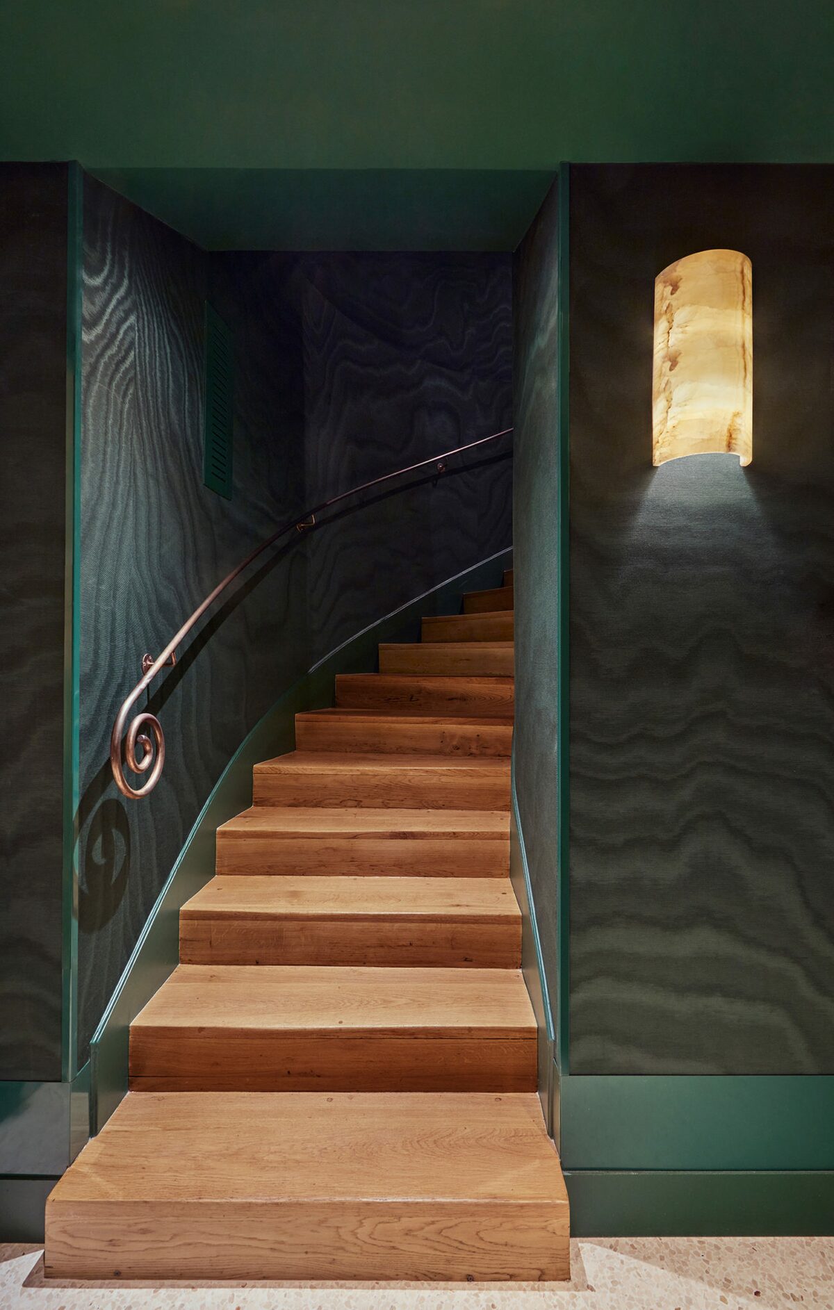 Escalier en bois avec papier peint moiré bleu nuit et rambarde en métal spirale - Projet Hôtel Spa Montalembert réalisé par Batiik Studio