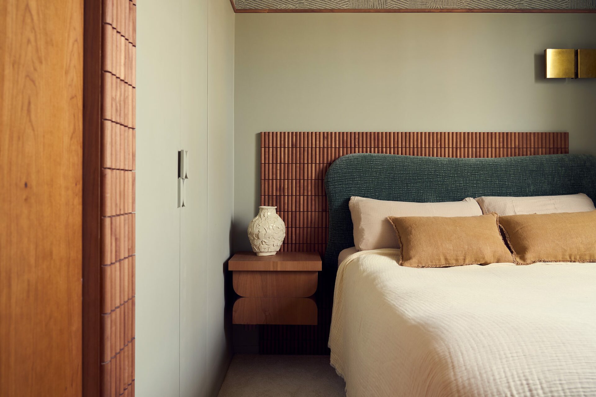 Chambre parisienne avec plafond avec papier peint à motif, murs vert d'eau et tête de lit en tissu et vase en céramique. Projet Saint-Gervais à Paris réalisé par Batiik Studio.