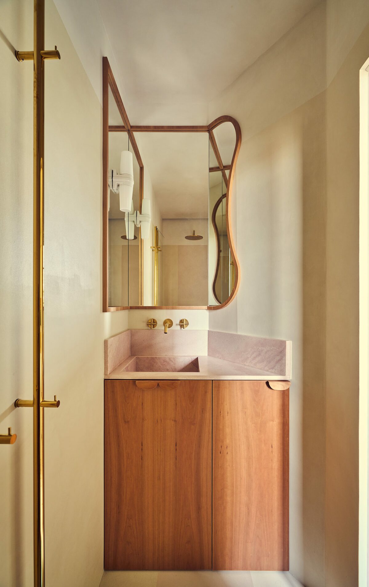 Salle de bain dans appartement parisien avec miroir en angle et vase en pierre rose. Projet Saint-Gervais à Paris réalisé par Batiik Studio.