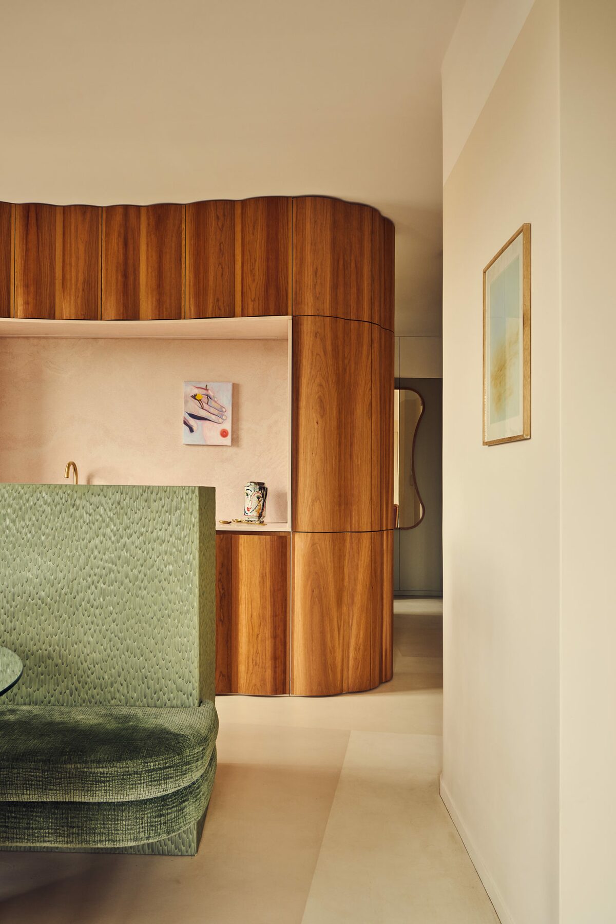 Banquette en tissu vert et cuisine en bois et pierre rose pâle. Projet Saint-Gervais réalisé par Batiik Studio.