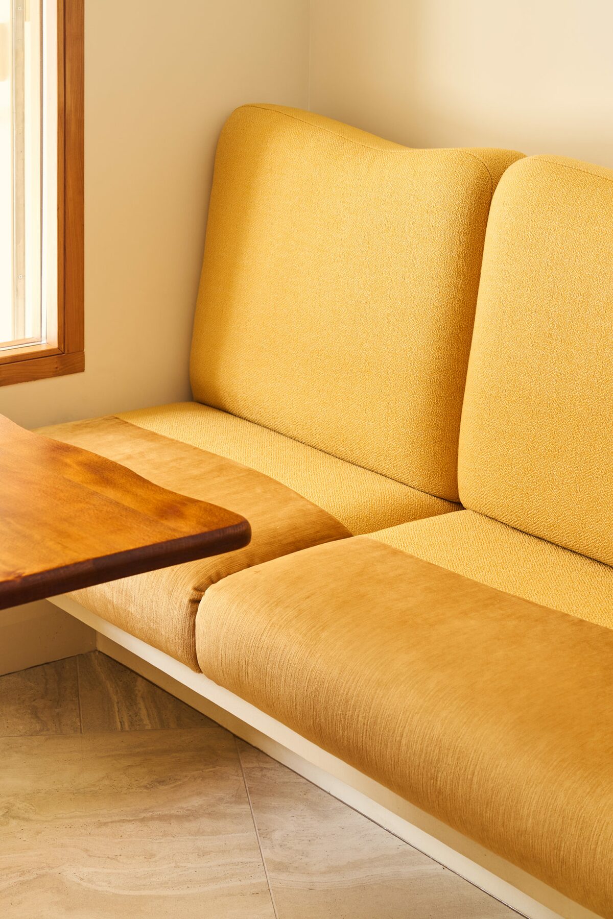 Banquette en velours jaune et tablette en bois. Projet Love à Paris réalisé par Batiik Studio.