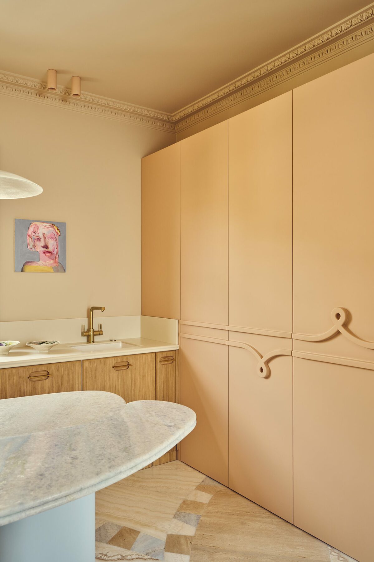 Cuisine haussmannienne avec rangements muraux beiges rosés. Carrelage et parquet. Projet résidentiel Joséphine à Paris réalisé par Batiik Studio.