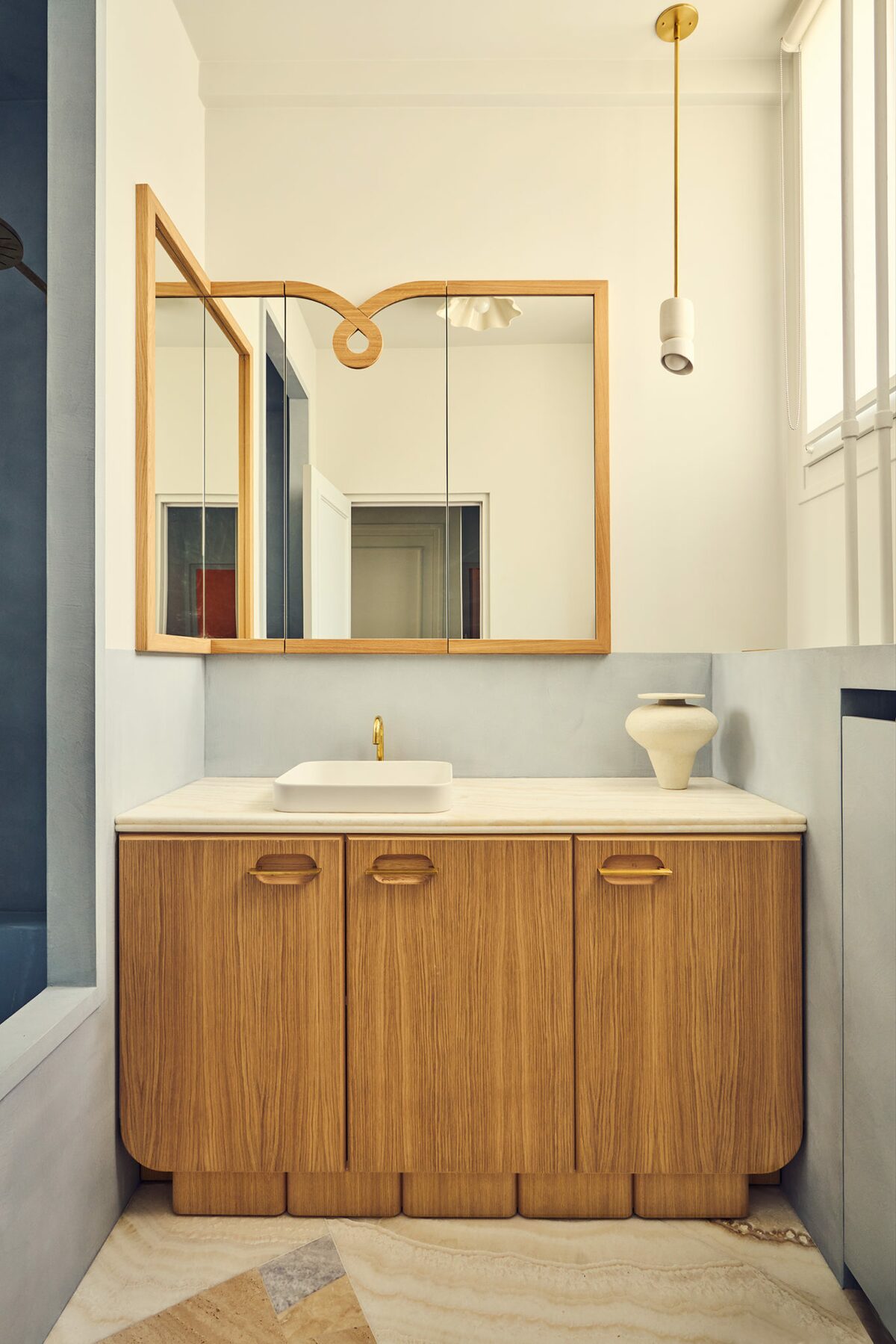 Salle de bain dans appartement haussamnnien chaux bleue avec baignoire dans une alcôve, miroir en bois. Projet Joséphine à Paris signé Batiik Studio.
