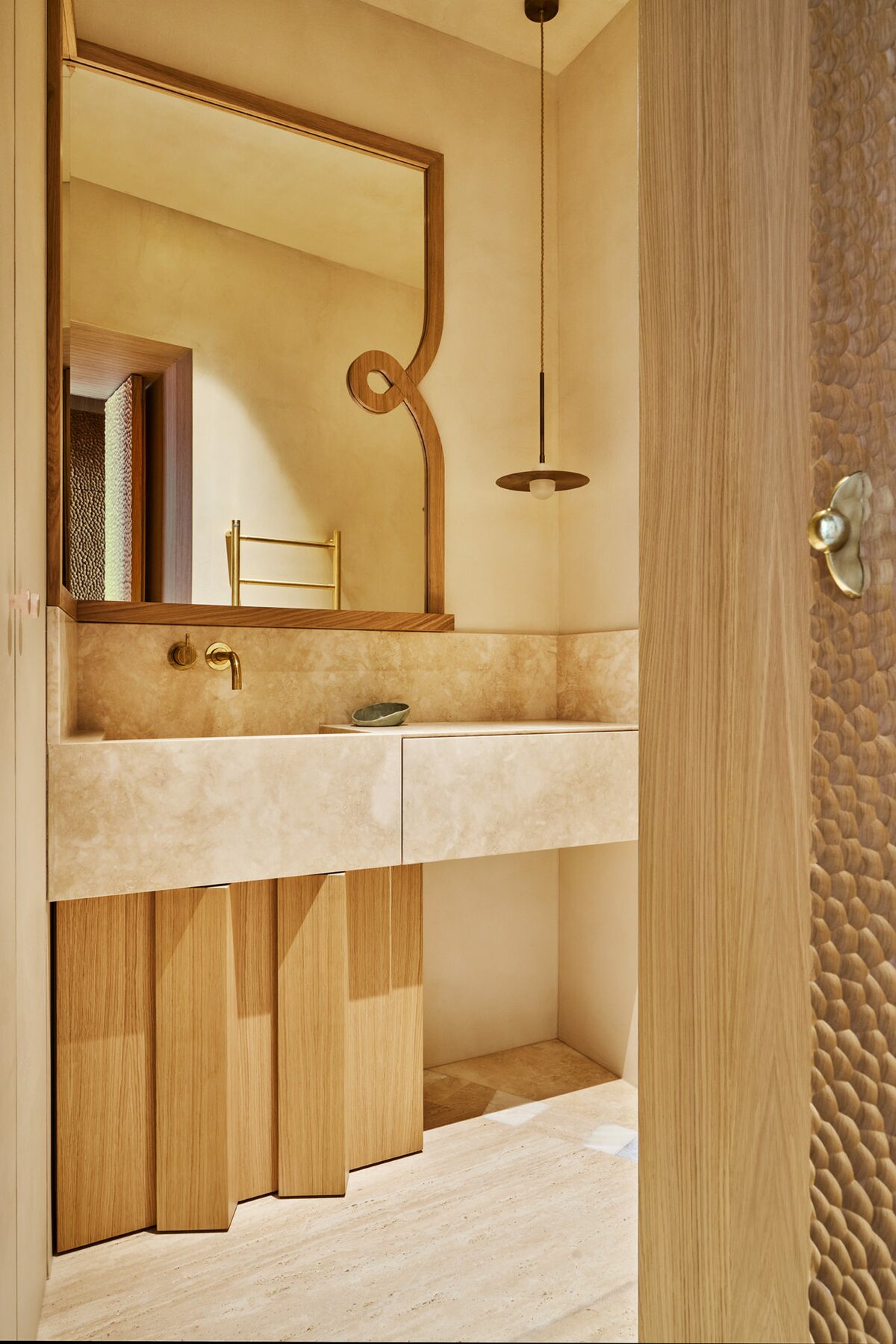Salle de bain dans appartement haussmamnien avec miroir en bois et vasque en marbre. Suspension bassse en métal. Projet Joséphine à Paris réalisé par Batiik Studio.