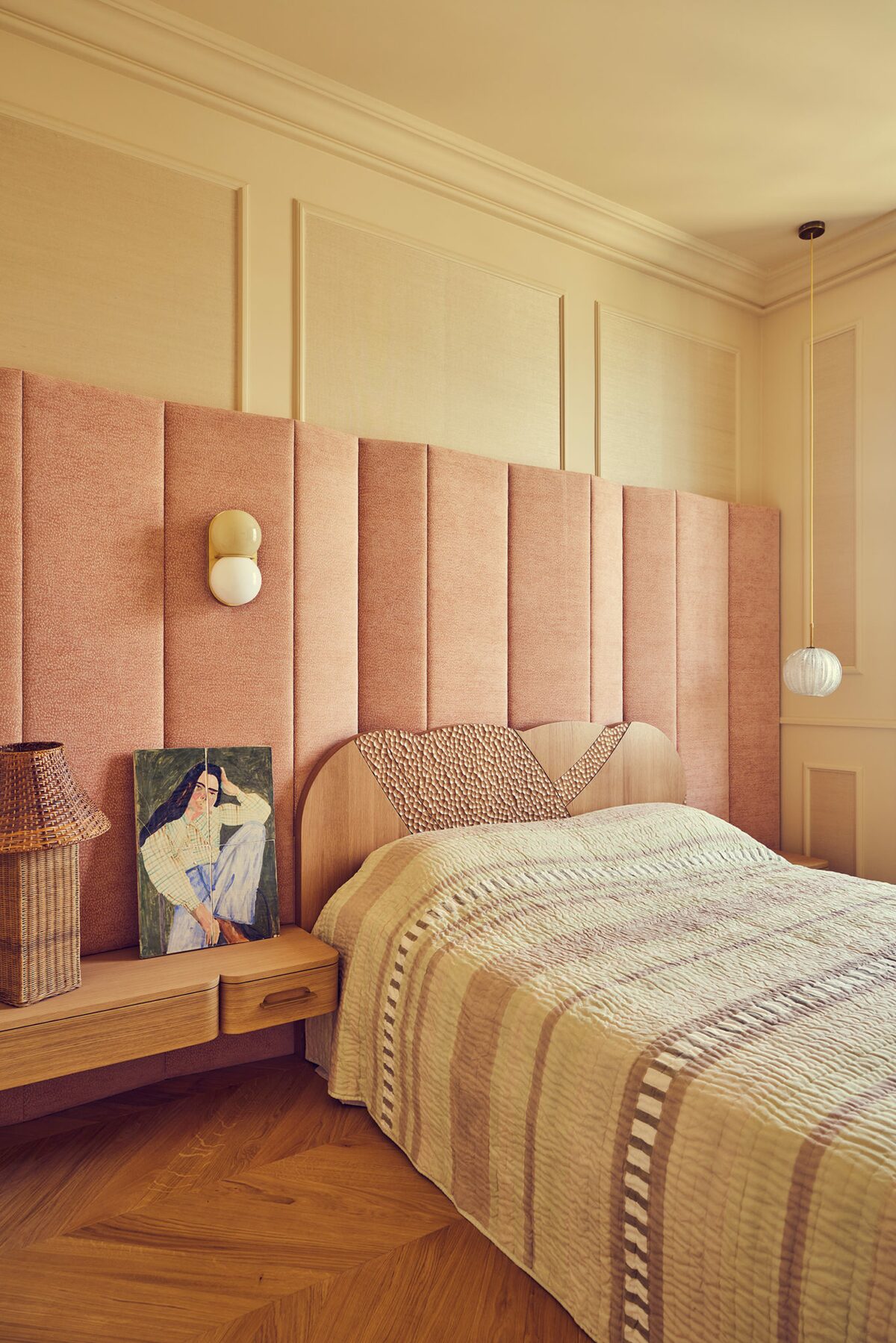 Chambre dans appartement haussmannien avec moulures beige rosé, tête de lit tissu, applique globe, lampe osier, dessus de lit rayé. Projet Joséphine réalisé par Batiik Studio.