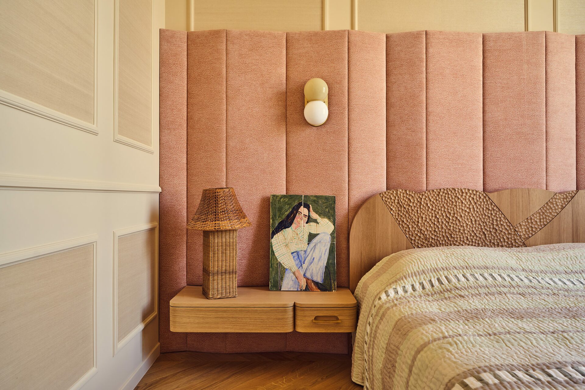 Chambre dans appartement haussmannien avec moulures beige rosé, tête de lit tissu, applique globe, lampe osier, dessus de lit rayé. Projet Joséphine réalisé par Batiik Studio.