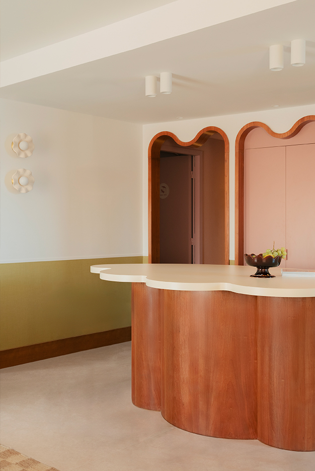 Espace cuisine avec ilôt central en bois, arche en courbe bois, frise murale vert olive. Style doux et méditerranéen, fantaisiste. Projet hôtelier Croisette d'Edgar Suite à Cannes réalisé par Batiik Studio.