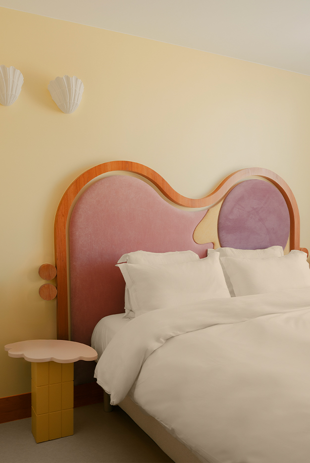 Suite parentale jaune pâle, appliques murales coquillages. Tête de lit en bois et textile. Style doux et méditerranéen, fantaisiste. Projet hôtelier Croisette d'Edgar Suite à Cannes réalisé par Batiik Studio.