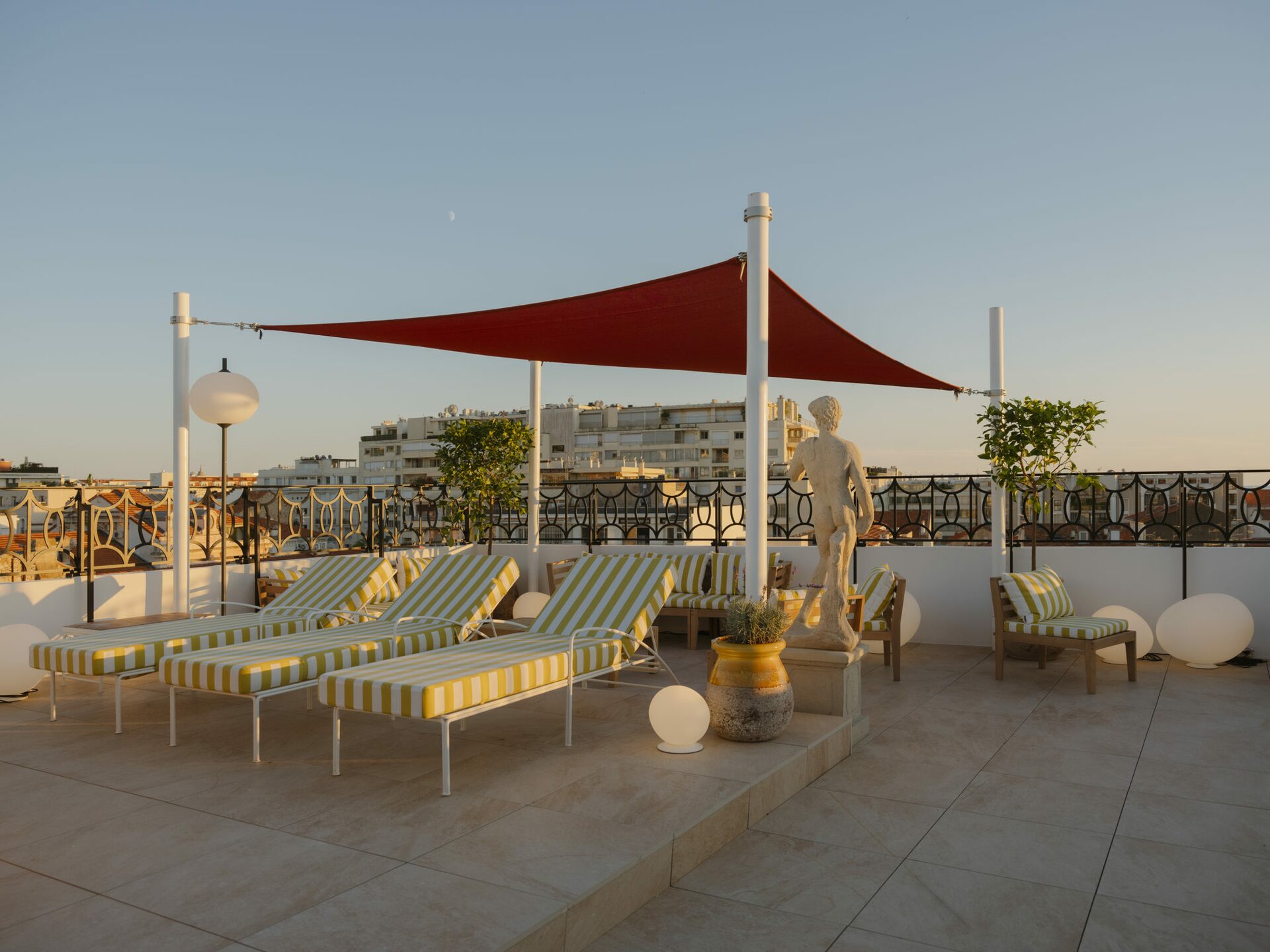 Terrasse rooftop avec transat avec assise en tissu rayé blanc et jaune. Projet hôtelier Croisette d'Edgar Suite à Cannes réalisé par Batiik Studio.