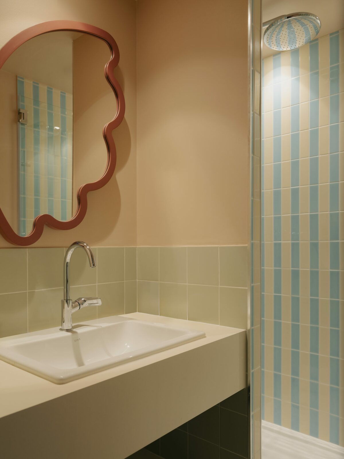 Salle de bain rose pâle avec carrelage rayés bleu et blanc. Style doux et vitaminé, fantaisiste. Projet hôtelier Croisette d'Edgar Suite à Cannes réalisé par Batiik Studio.