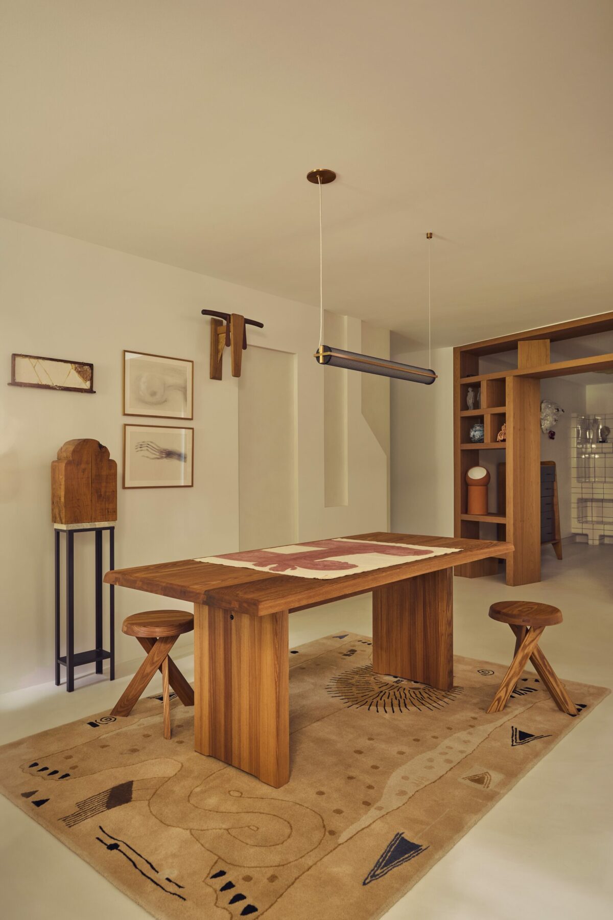 Atelier avec bibliothèque-niche en bois, tapis Lion Toulmondebochart, tabouret: Vintage, Pierre Chapo, table vintage, suspension Juniper Studio / Galerie Triode, Lampe à poser Serax.