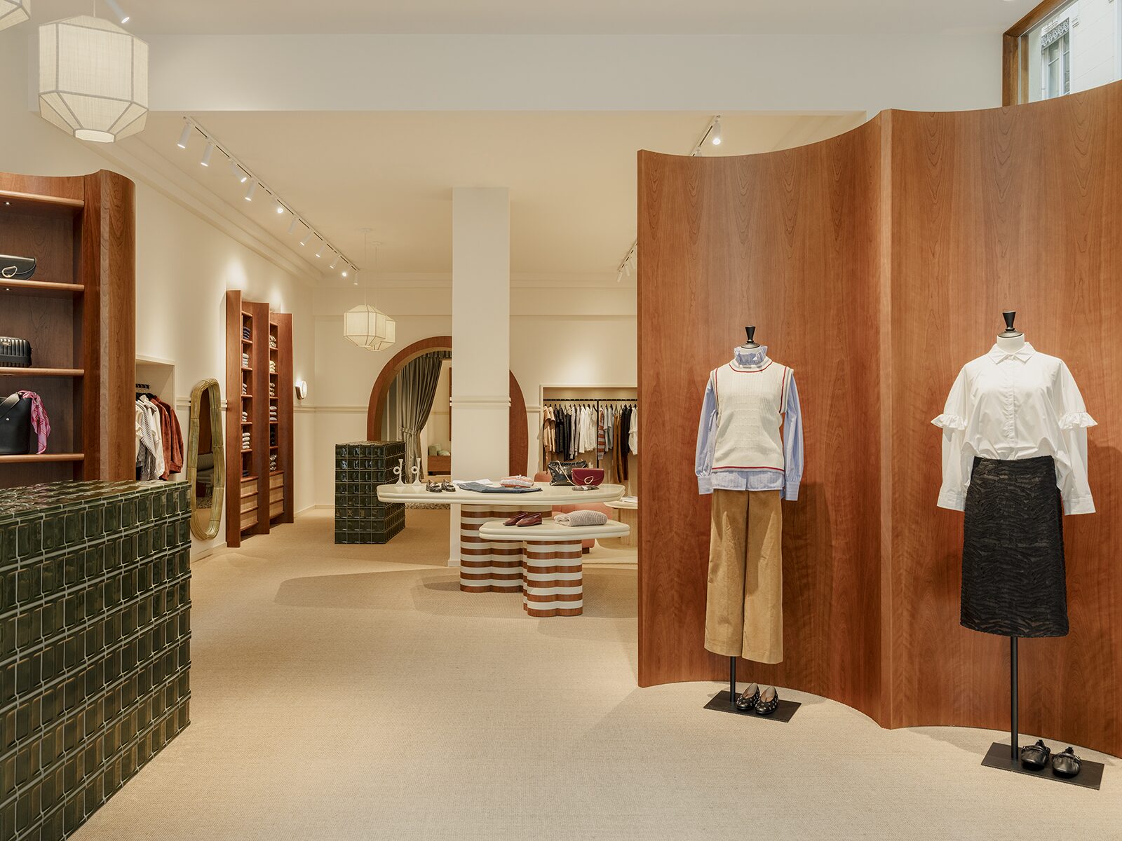 Comptoir en carrelage vert et table de présentation avec pied rayé blanc et rouge, paravent en bois merisier dans l'adresse lyonnaise de Balzac Paris réalisée par l'agence d'architecte Batiik Studio.