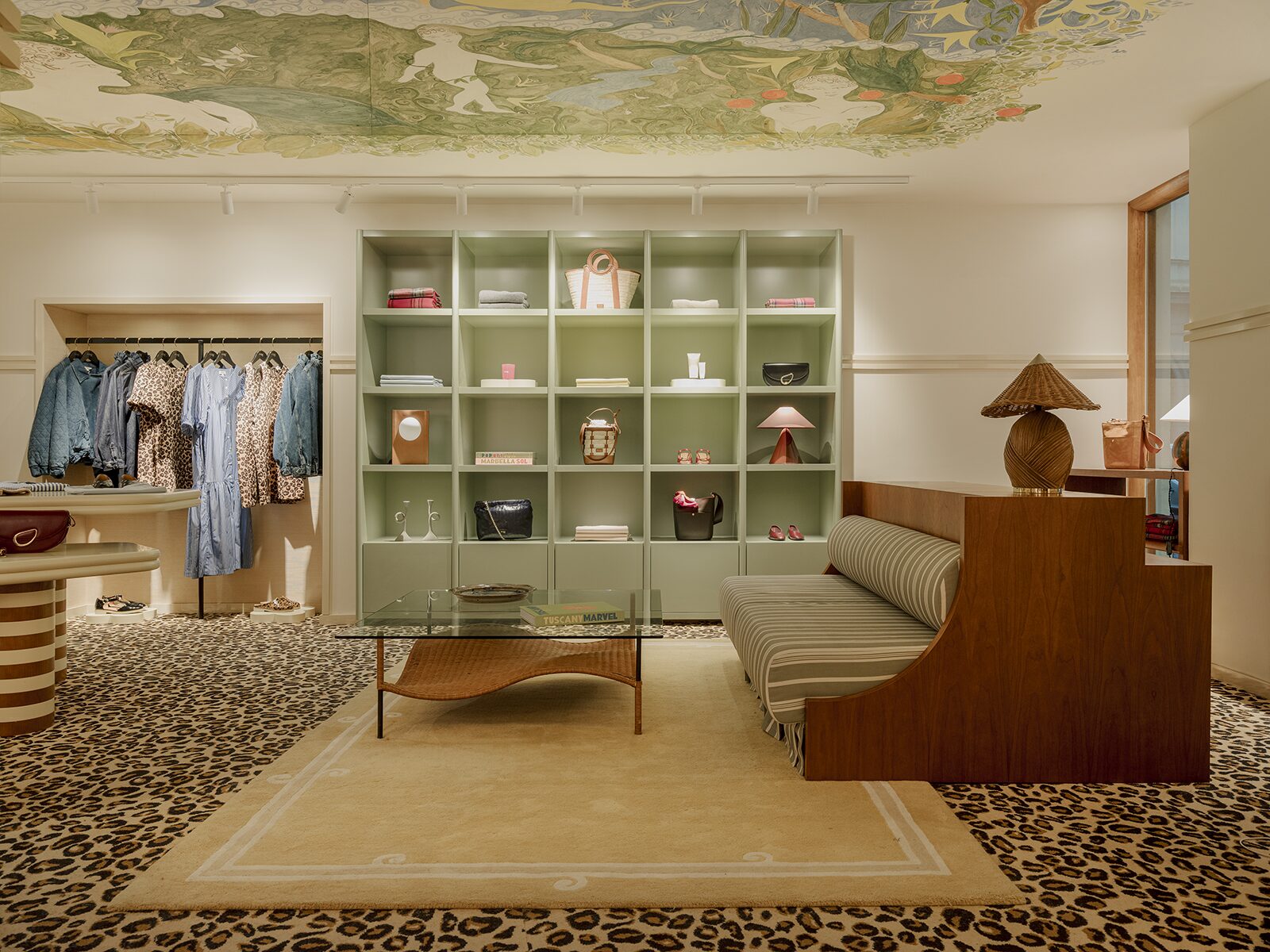 Boutique avec moquette léopard et banquette rayurée. Fresque peinture au plafond et étagère murale vert clair. Un projet réalisé par Batiik Studio pour Balzac Paris dans son adresse lyonnaise.