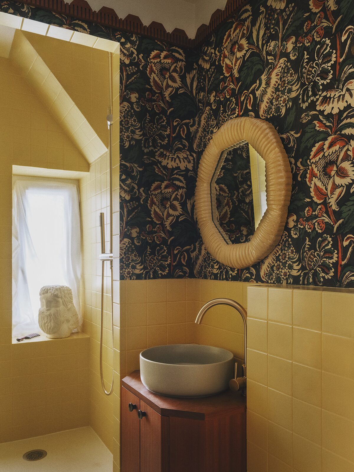 Salle de bain jaune avec papier-peint motifs floraux Antoine Poisson, miroir rond jaune, carrelage jaune. Projet Chevalier réalisé à Paris par Batiik Studio.